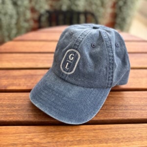 Griffith Leagues Club navy washed cap with embroidered GL logo on timber outdoor table