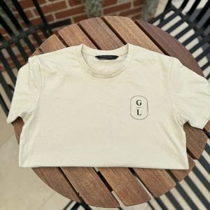 Sand Griffith Leagues Club t-shirt with GL chest logo laid flat on timber table